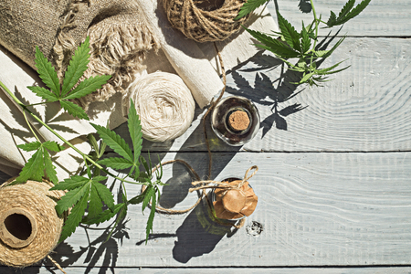 Hemp oil, canvas and threads on a white wooden surfaceの写真素材