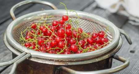 Red currant in a colander on a black wooden tableの写真素材
