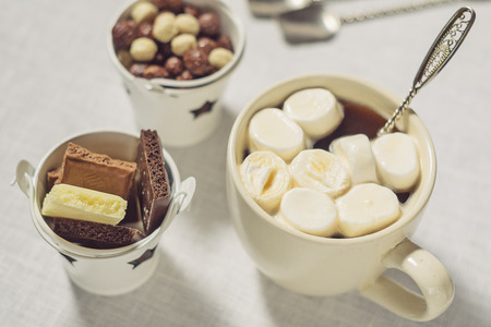A cup of coffee with marshmallows and chocolate on a white backgroundの写真素材