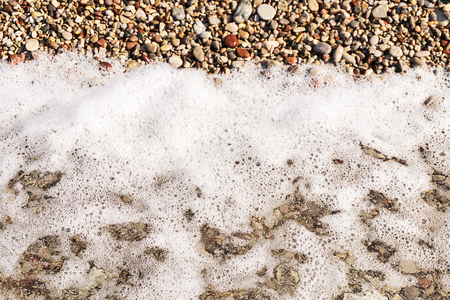 Colorful sea pebbles on the shore and clear waterの写真素材