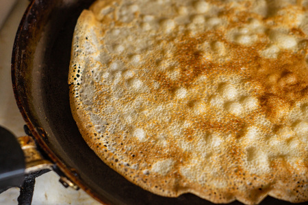 Cooking thin pancakes in a pan on the stoveの写真素材