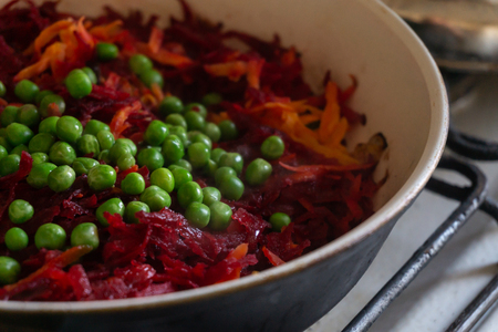 Green peas, beets and carrots stew in a frying pan on the stoveの写真素材