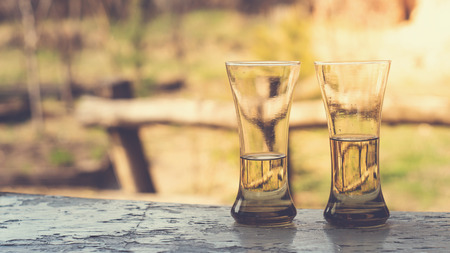 Two glasses with wine or juice on a wooden table in the gardenの写真素材