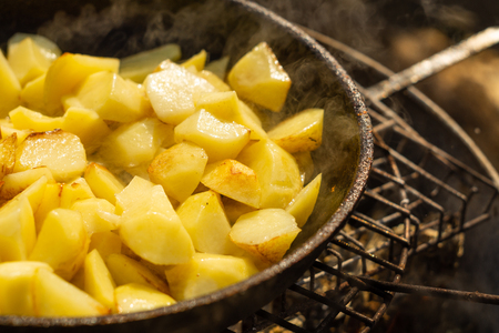 Potatoes fried in a frying pan on a grill outdoorsの写真素材