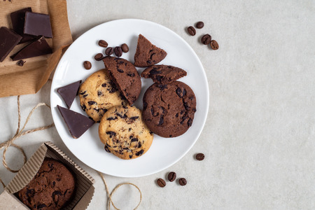 Oatmeal cookies with cocoa and chocolate on a white plate and in a cardboard box