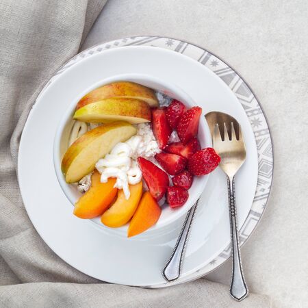 Light vitamin breakfast. Sliced strawberry, apricot and apple with cottage cheese and sour cream. Top viewの写真素材