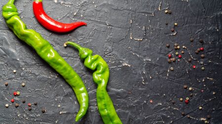 Pods of green and red chili peppers on a black textured backgroundの写真素材