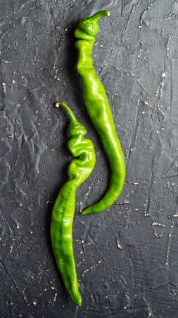 Two pods of green chili peppers on a dark backgroundの写真素材