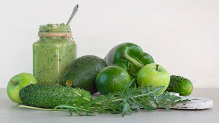 Green smoothie of apple, cucumber, avocado and pepper in a glass jar, whole ingredients on a white backgroundの写真素材
