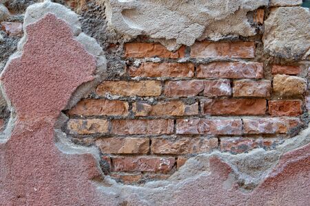Old brickwork of red and yellow bricks with fragments of plasterの写真素材