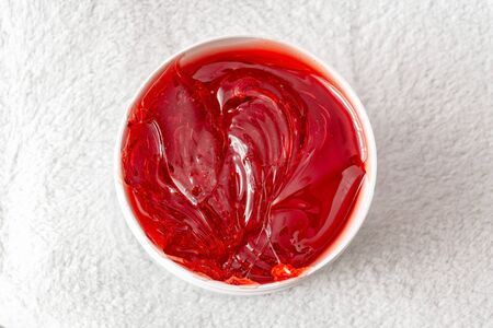 Red transparent shugaring paste in a white jar. Close-upの写真素材