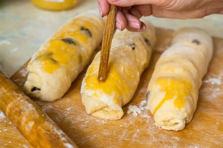 Confectioner hand greases yeast dough pies with raw egg yolk