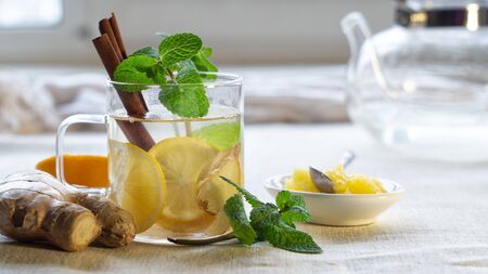Ingredients for a hot drink with lemon, ginger, mint and honey in a glass cupの写真素材