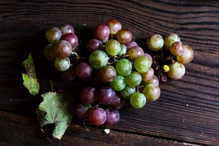 Bunch of ripe green and red grapes on a wooden table. Top viewの写真素材