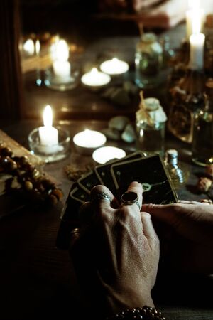Magic and occultism. Hands of a sybil with fortunetelling cards and burning candles is reflected in an old mirrorの写真素材
