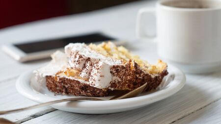 Tiramisu cake in a plate, smartphone and a cup of coffee. Traditional italian dessert