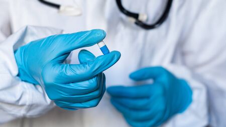 Doctor or pharmacist hand holds capsule with medicine