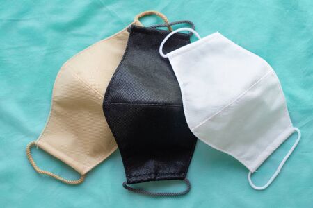 Stack of homemade protective reusable antiviral masks on green cloth