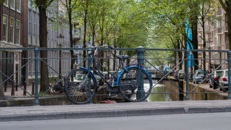Bicycle parked near a city canal in Amsterdam, Netherlandsの写真素材