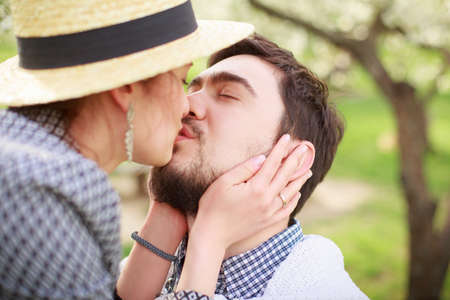 A young girl in a straw hat kisses a guy. Loving couple in the garden.の写真素材