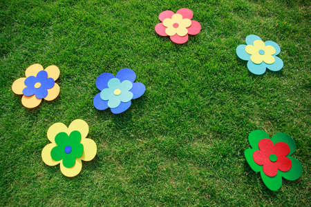 Big multicolored flowers from felt on a green grass background for children's games outdoors in the park.の写真素材