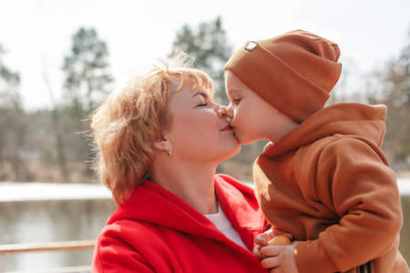 Grandson tender and heartwarming kissing elderly grandmother. Nature walk near the lake in the...