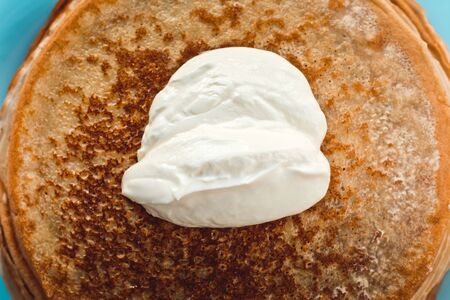 pancakes with sour cream are stacked on top of each other in close-upの写真素材