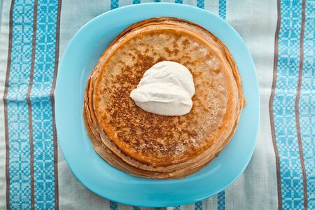 pancakes with sour cream are stacked on top of each other on a blue plate