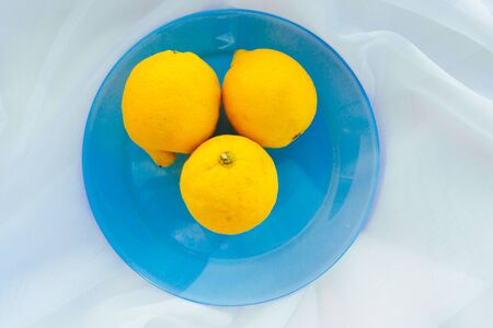 whole yellow lemons on a blue plate. the view from the topの写真素材