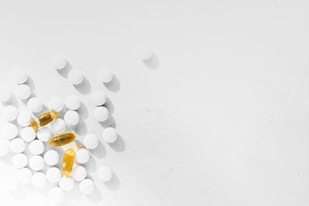 a lot of white round tablets and a few yellow capsules lying on a white background. the view from the topの写真素材