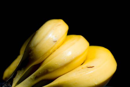 a bunch of ripe yellow banana fruits on a dark background of a drop of water. washed, clean fruitの写真素材