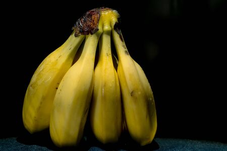 a bunch of ripe yellow banana fruits on a dark background of a drop of water. washed, clean fruitの写真素材