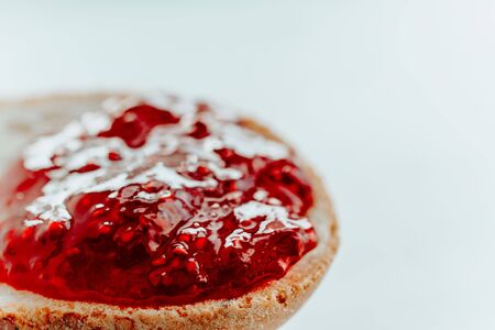 raspberry jam on a piece of bread close up on a white backgroundの写真素材