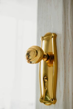 the door handle of the yellow metal on a white wooden door.の写真素材