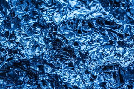 blue background of crumpled foil. shiny metal foil as a blue background or textureの写真素材