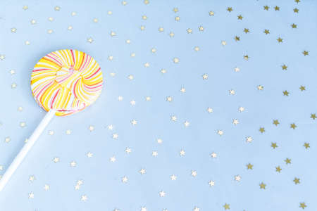 Round multicolored Lollipop, blue background with gold bright confetti. Flat styling style. Holiday...