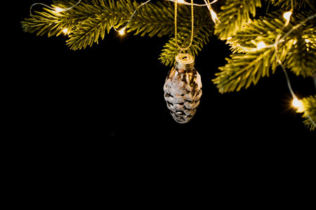 one Christmas tree toy pinecone on the green branches of the tree. Bright lights garlands on the...