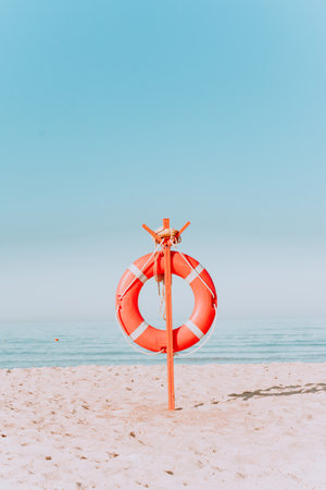 red lifebuoy on a sandy beach in pastel colors. Red lifebuoy on the sandy shore of the beach on a sunny day.の写真素材