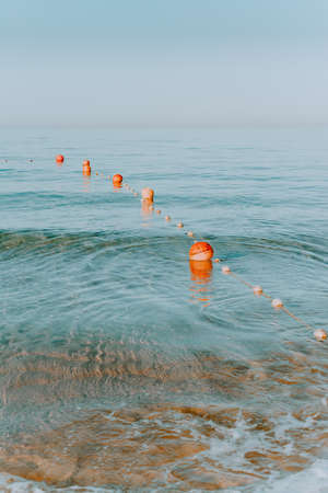one floating orange sea buoy in the sea. Orange boat buoy in the sea. border of the bathing place. The orange buoy on the dark sea waterの写真素材