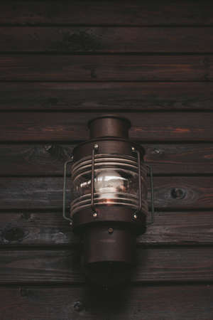 outdoor lighting with a retro-style lantern. an old lantern on a wooden wall. vertical photo.brown...