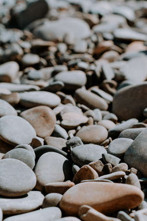 Gray and brown sea pebbles on a sunny day. close-up. hard shadows. the image is in pastel colors. vertical photoの写真素材