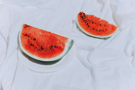 a piece of red ripe watermelon on a white plate on a table with a white tablecloth. Side view. Horizontal image. watermelon seedsの写真素材