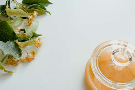 a glass jar of honey with linden flowers on a white background.The concept of healthy eating. Treatment of colds with honey. horizontal imageの写真素材