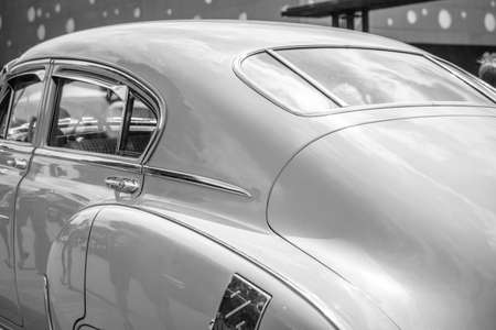 Retro-styled back of a classic car with headlights in black and white image. The headlights are...