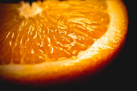 Juicy slice of orange close-up on a dark background. A cut slice of orange is a side view. ingredients for juice. Background imageの写真素材