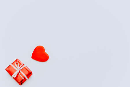 The concept of Valentines Day. A red stuffed toy heart and a red gift box with a white ribbon on a light background. Banner. Copy the space of your text. Greeting cardの写真素材