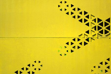 iron wall background texture material steel metal plate paint surface with industrial yellow color and triangle black hole striped pattern for urban fence panel structure architecture outdoor designの写真素材