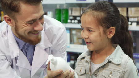 A young customer chooses which item to buy with the help of an apothecaryの写真素材