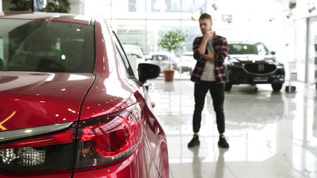Male customer rubbing beard thoughtfully choosing a new car at the dealership
