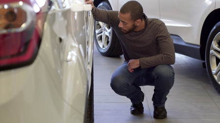 Man looks at the car wheel at the dealershipの写真素材
